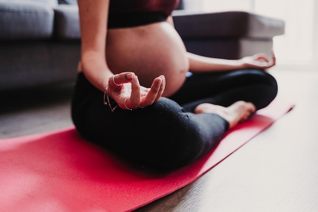 Seção inferior de mulher grávida se exercitando enquanto está sentada em casa