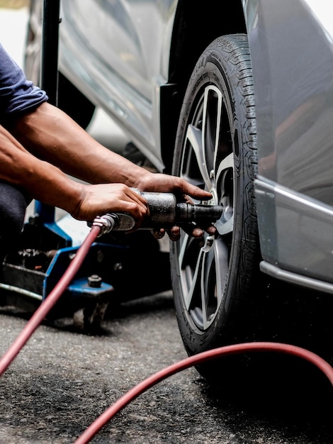 Seção inferior de um homem mudando um pneu de carro