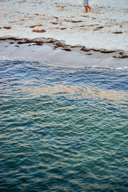 Foto seção inferior de uma criança a caminhar na praia