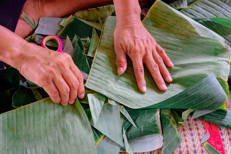 Foto seção inferior de uma mulher cortando uma folha de banana