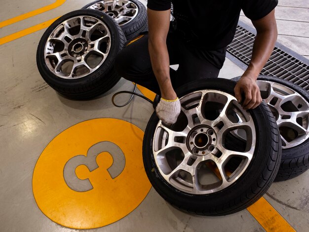 Foto seção inferior do mecânico segurando pneus na garagem