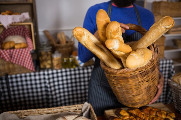 Seção intermediária da equipe segurando uma cesta de vime de pães franceses no balcão