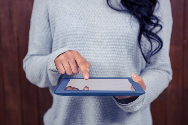 Seção intermediária da mulher asiática usando tablet contra parede de madeira