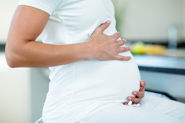 Seção intermediária da mulher grávida tocando sua barriga