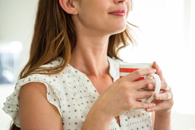 Seção intermediária da mulher segurando a xícara de café