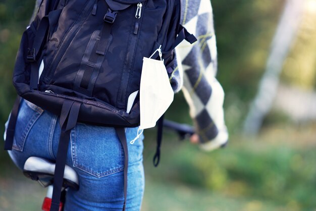 Seção intermediária de adolescente indo de bicicleta para a escola com máscara protetora