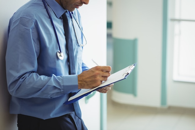 Foto seção intermediária do médico escrevendo na área de transferência