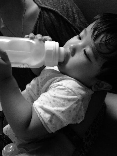 Foto seção média da mãe carregando o bebê bebendo leite da garrafa