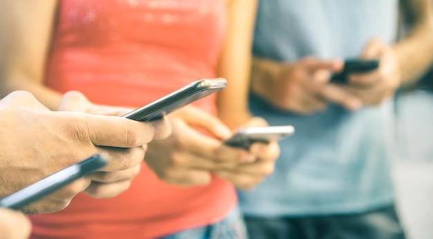 Seção média de amigos usando telefones celulares enquanto estão ao ar livre