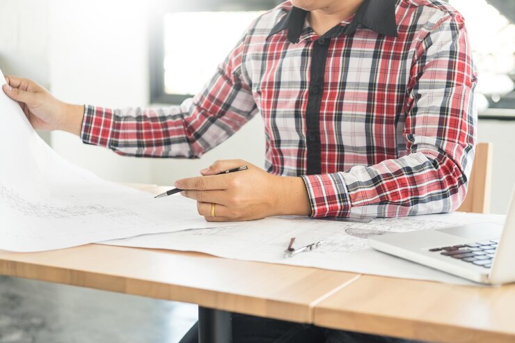 Foto seção média de arquiteto com planos sentados na mesa