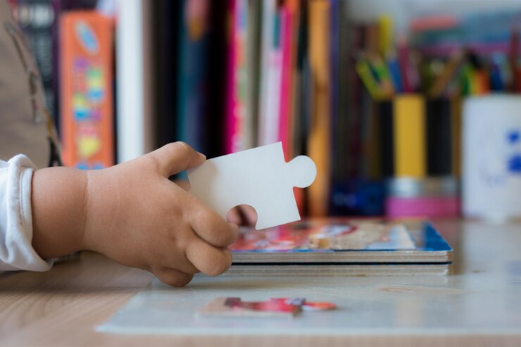 Foto seção média de bebê segurando peça de quebra-cabeça na mesa