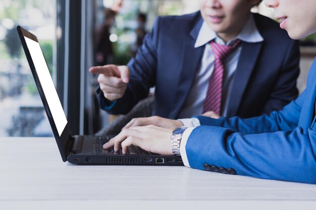 Seção média de colegas discutindo sobre laptop na mesa em um café