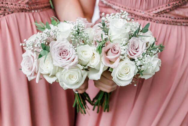 Seção média de damas de honor segurando buquês