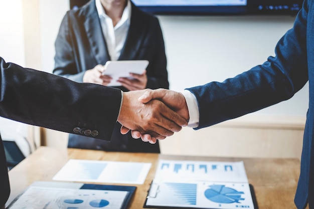 Seção média de empresários apertando as mãos sobre a mesa no escritório