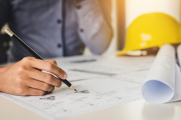 Seção média de engenheiro com lápis analisando o plano na mesa