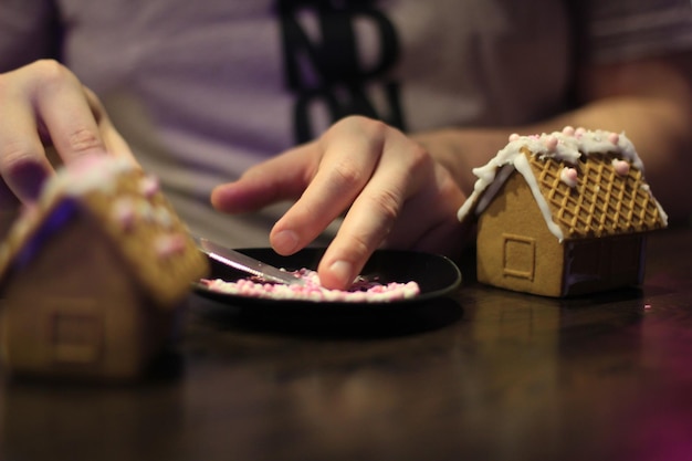 Foto seção média de homem decorando casas de pão de gengibre com pérolas de açúcar em prato na mesa