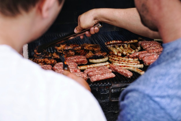 Seção média de homens preparando comida em churrasqueira