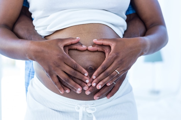 Seção média de marido e mulher fazendo forma de coração