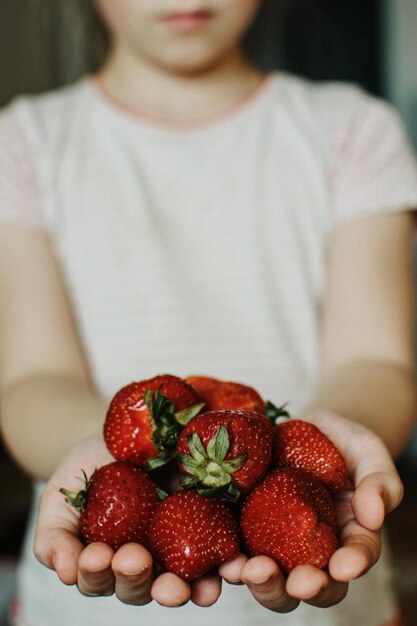 Foto seção média de menina segurando frutas em casa