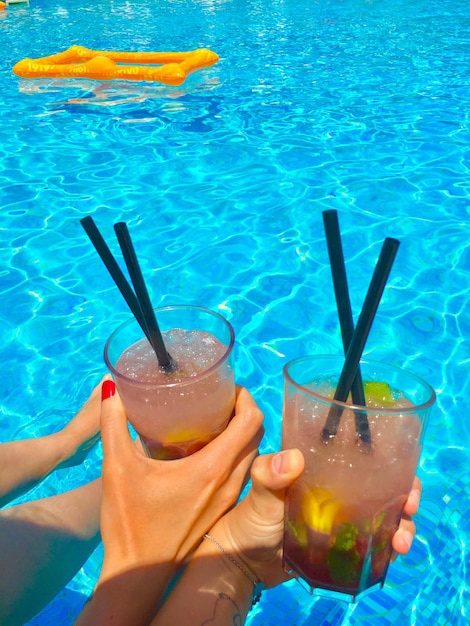 Foto seção média de mulher bebendo água na piscina