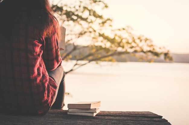 Foto seção média de mulher com livro sentada no lago