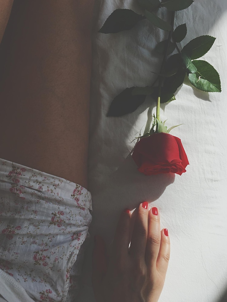 Foto seção média de mulher com rosa na cama
