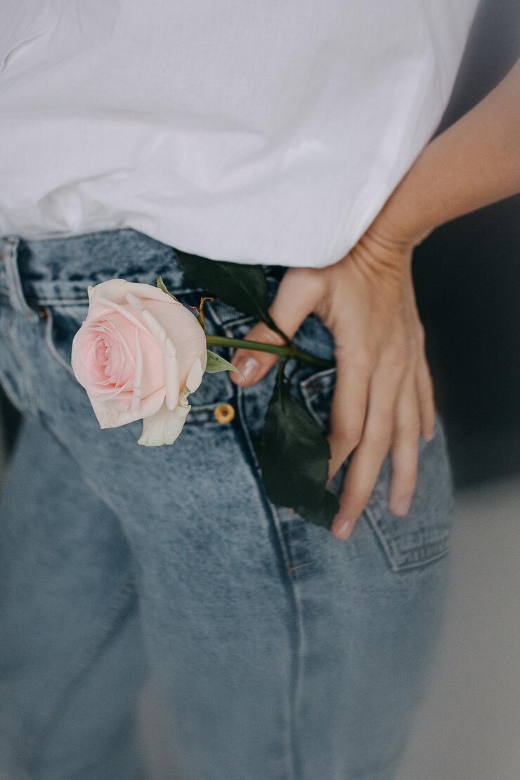 Foto seção média de mulher com rosa no bolso de calça jeans