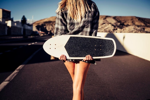 Seção média de mulher com skate de pé na estrada