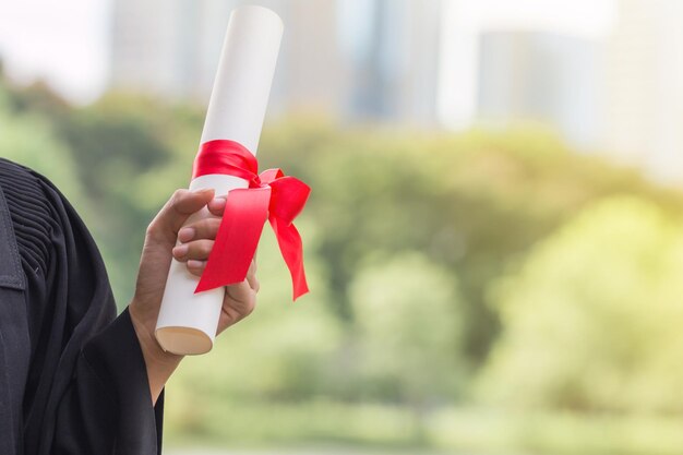 Foto seção média de mulher em vestido de formatura segurando certificado