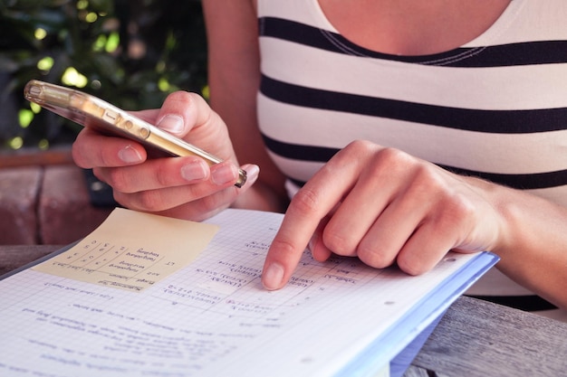 Foto seção média de mulher estudando enquanto usa smartphone na mesa