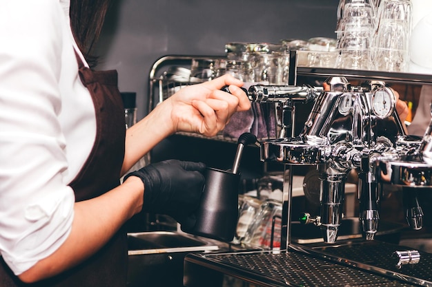 Seção média de mulher fazendo café na cafeteria