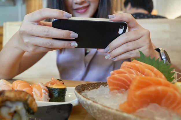 Foto seção média de mulher fotografando comida com telefone celular na mesa