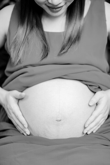 Seção média de mulher grávida com as mãos no estômago em casa