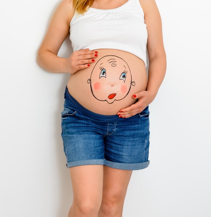 Foto seção média de mulher grávida com barriga pintada de pé contra fundo branco