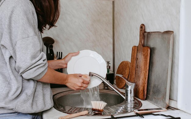 Foto seção média de mulher lavando pratos