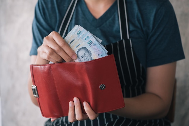 Seção média de mulher segurando bolsa com moedas de papel