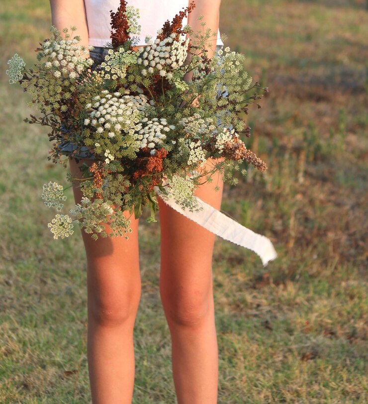 Foto seção média de mulher segurando flores enquanto está de pé em terra
