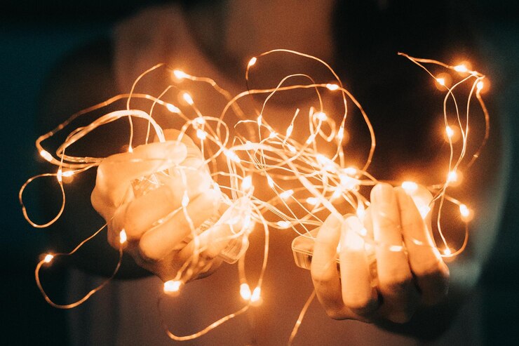 Foto seção média de mulher segurando luzes de corda iluminadas em uma sala escura
