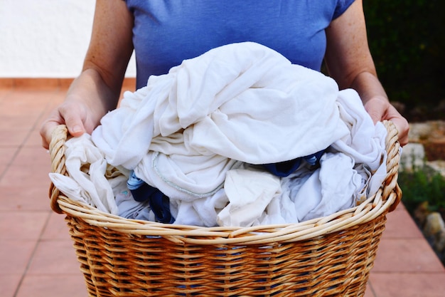 Seção média de mulher segurando roupa lavadora em uma cesta no quintal