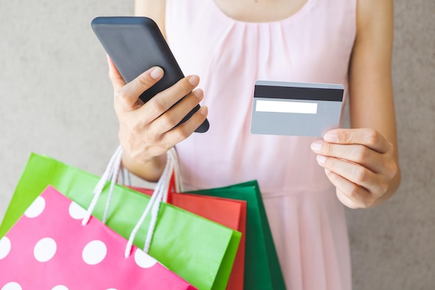 Foto seção média de mulher segurando sacos de compras contra a parede