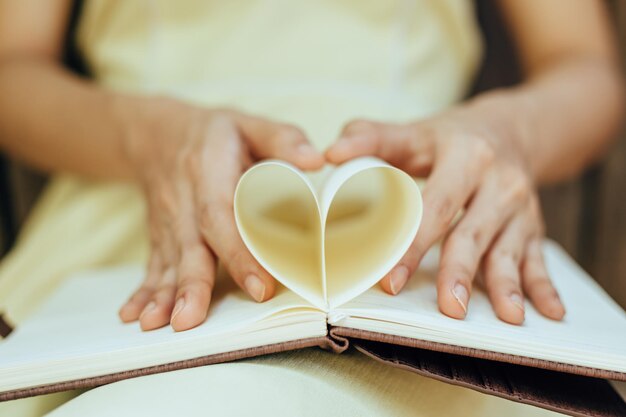 Foto seção média de mulher segurando um livro em forma de coração