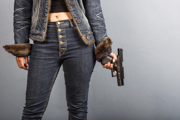 Foto seção média de mulher segurando uma arma enquanto está de pé junto à parede