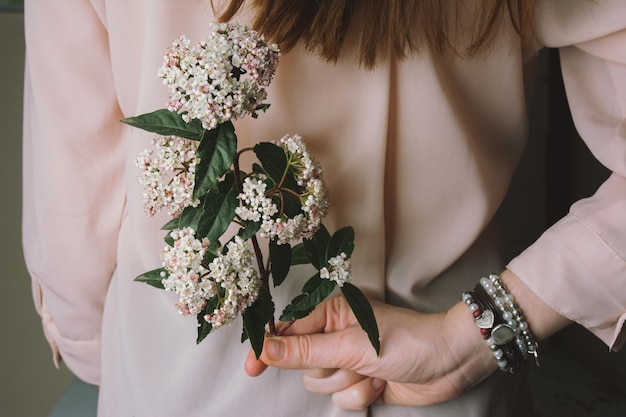 Seção média de mulher segurando uma flor atrás das costas