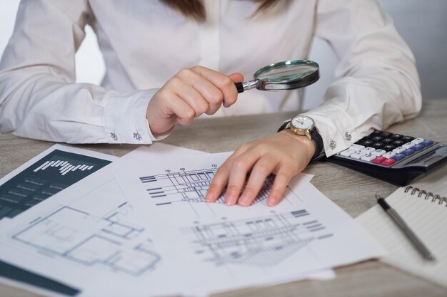 Seção média de mulher segurando uma lupa sobre papel na mesa