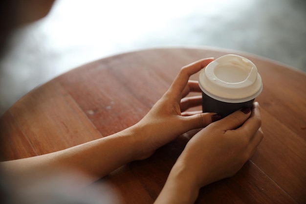 Foto seção média de mulher segurando xícara de café na mesa