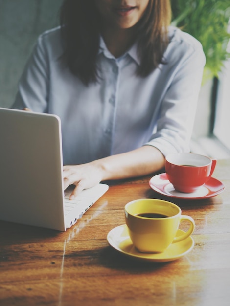 Seção média de mulher usando laptop em um café