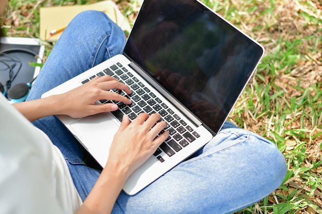 Seção média de mulher usando laptop enquanto está sentada no parque