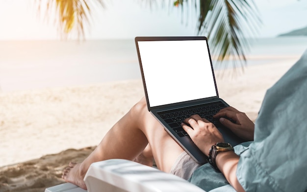 Seção média de mulher usando laptop na praia