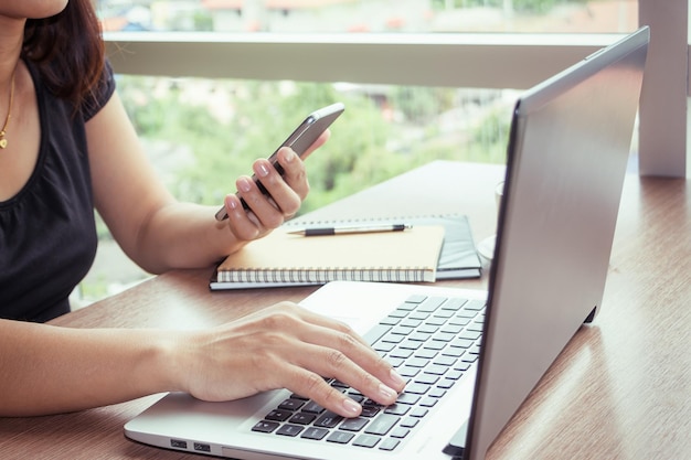 Foto seção média de mulher usando telefone celular e laptop na mesa