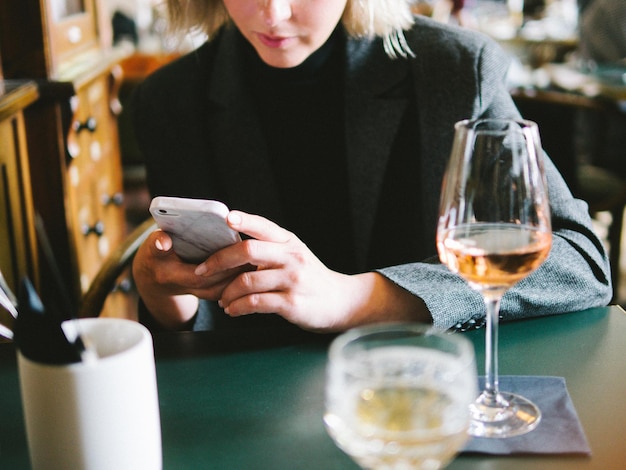 Seção média de mulher usando telefone em um restaurante